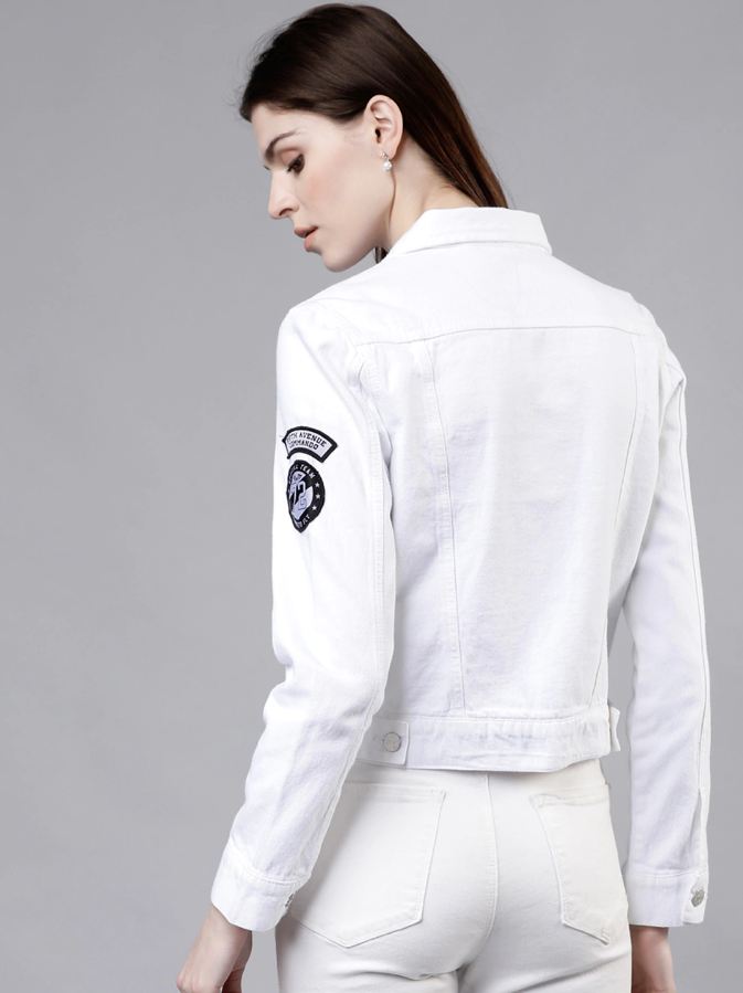 Classic white women's denim jacket with logo patch on sleeve, featured against a plain gray background.