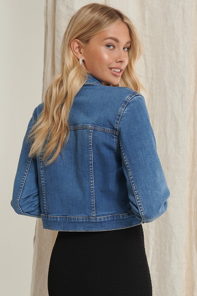 Blue women's denim jacket with button closure and collared design, displayed on a smiling young blonde model.
