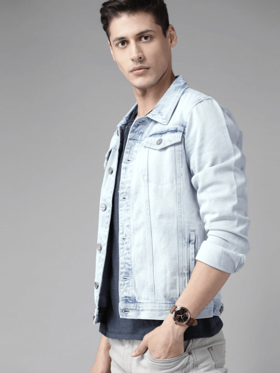 Light blue denim jacket with man wearing a casual outfit and posing against a gray background