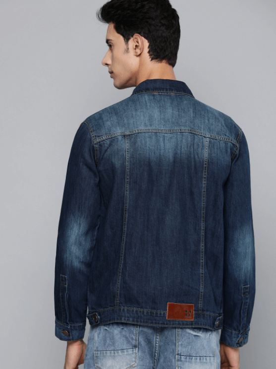 Dark blue denim jacket with traditional collar and chest pockets, worn by a young man with dark hair.