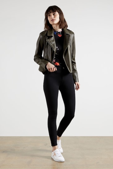 Stylish woman in sleek leather jacket, skinny black jeans, and white sneakers showcasing a contemporary, chic look.