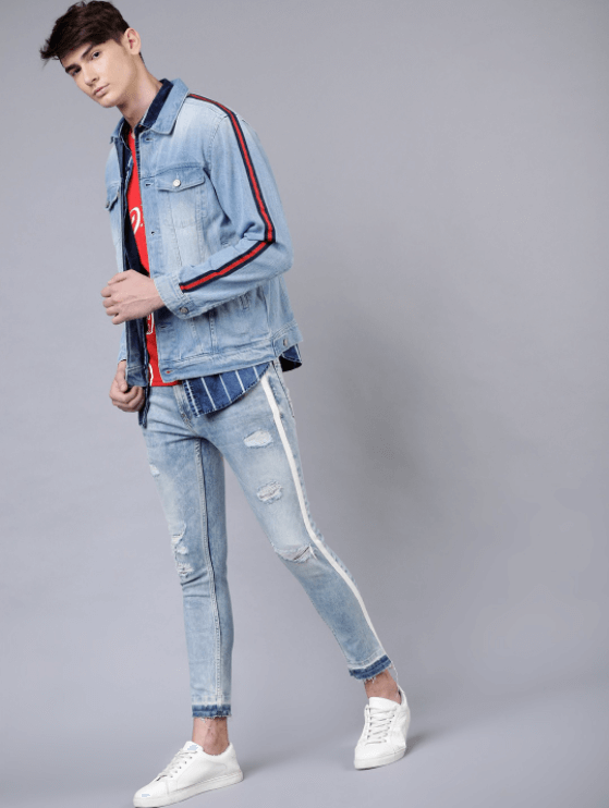 Trendy light blue denim jacket with side stripes on male model posing against plain background.