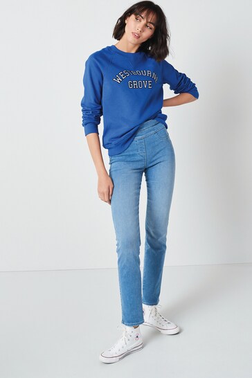 Vibrant blue hooded sweatshirt with "YES QUEEN'S GROVE" text, paired with light-wash high-waisted slim-fit jeans and white sneakers, creating a casual yet stylish look for the young female model.