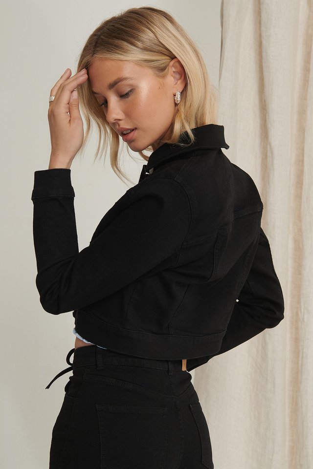 Stylish black denim jacket for women, featuring ruffle collar and belted waist design.