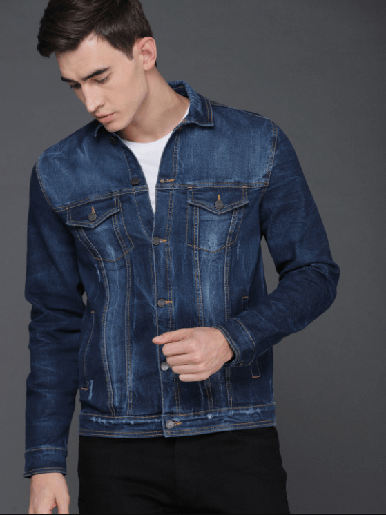 Dark blue denim jacket with distressed details, worn by a young man in a studio setting.