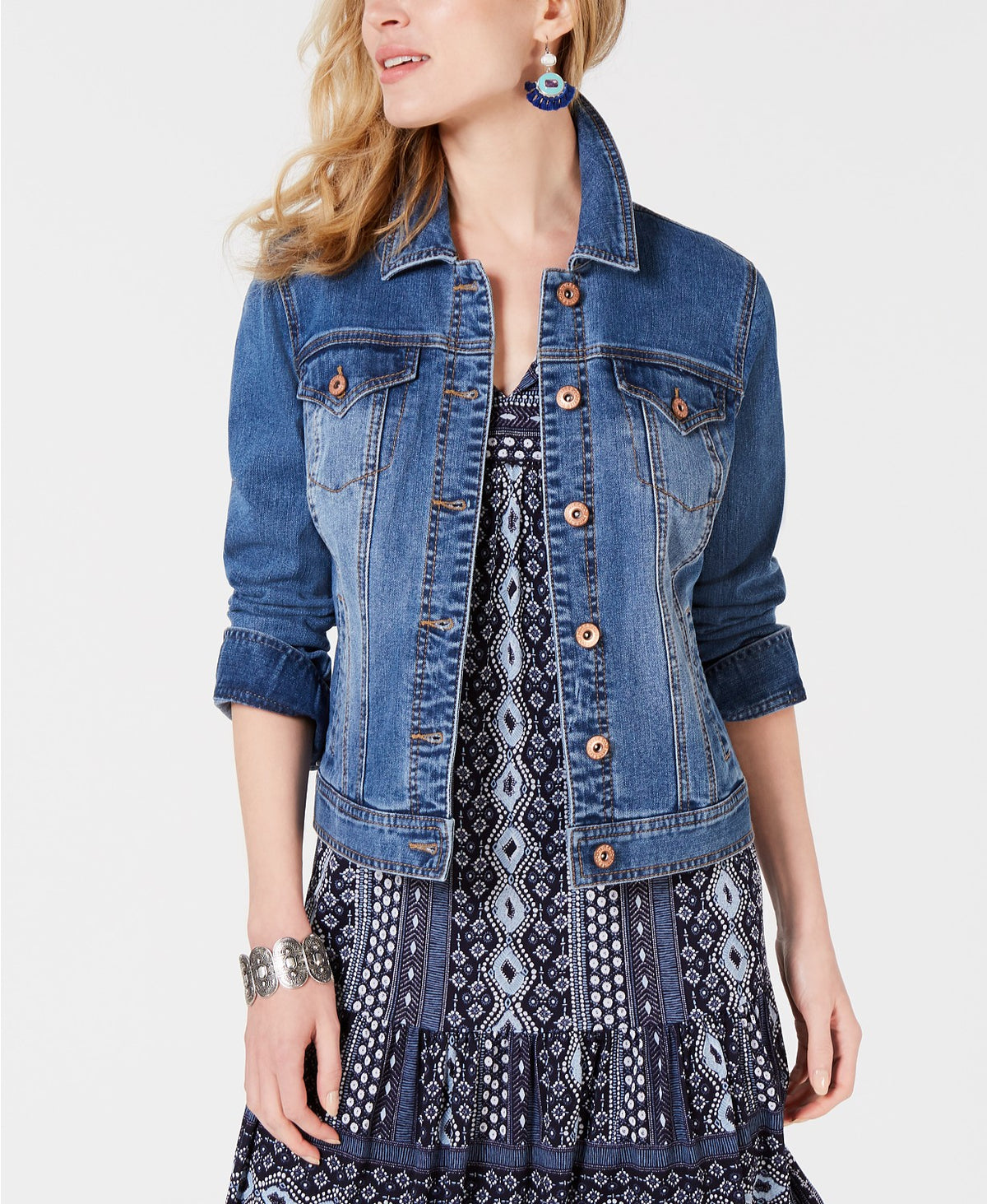 Stylish women's blue denim jacket with button detailing, worn over a patterned dress in the image.