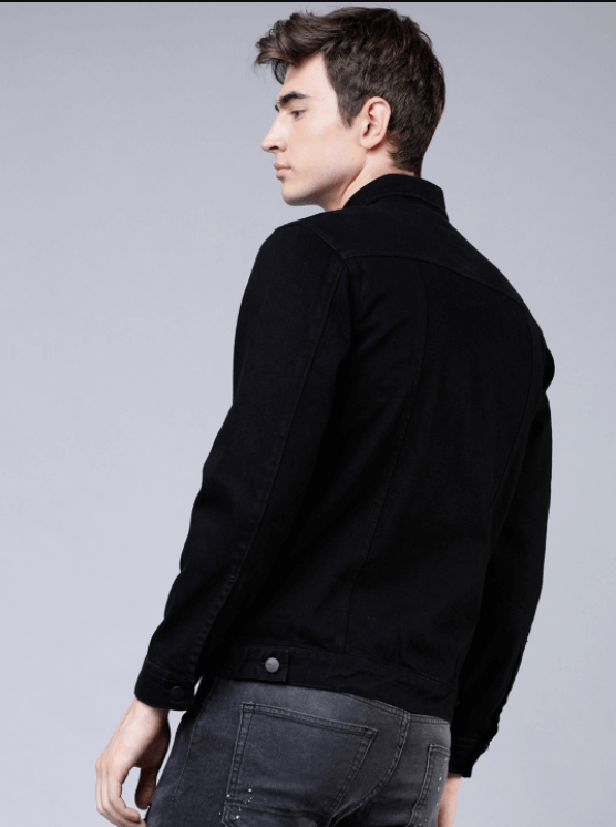 Stylish man wearing a black denim jacket against a light background