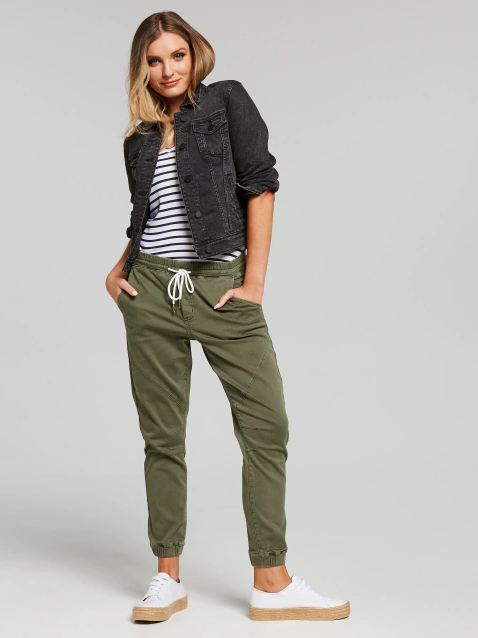 Stylish woman's denim jacket, striped top, olive green jogger pants, and white sneakers