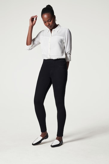 Elegant SPANX® Medium Control Jean Ish Shaping Skinny Jeggings worn by a stylish woman in a white blouse and black pants.