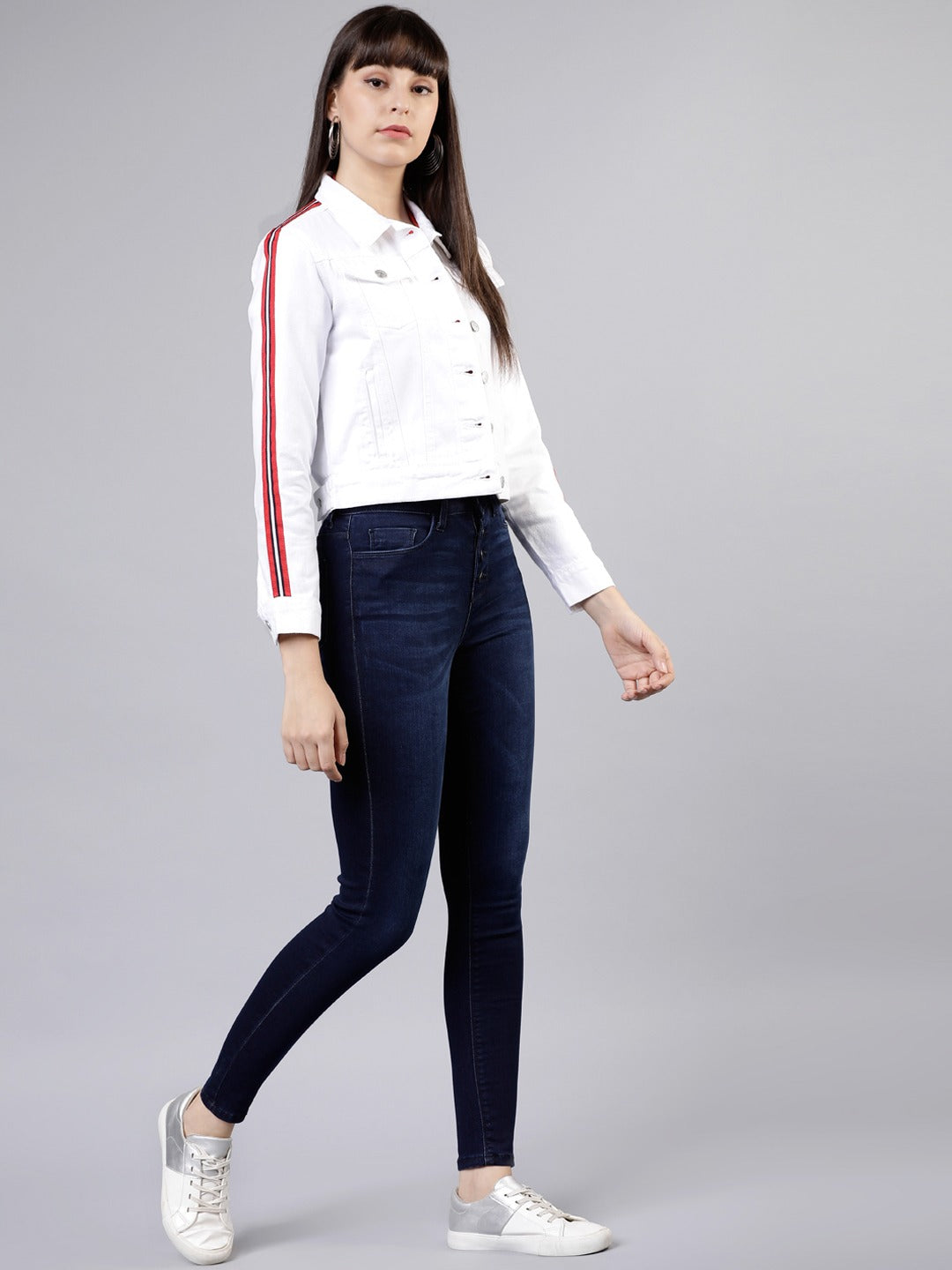 White women's denim jacket with red stripes, paired with navy skinny jeans and white sneakers, showcased against a plain background.