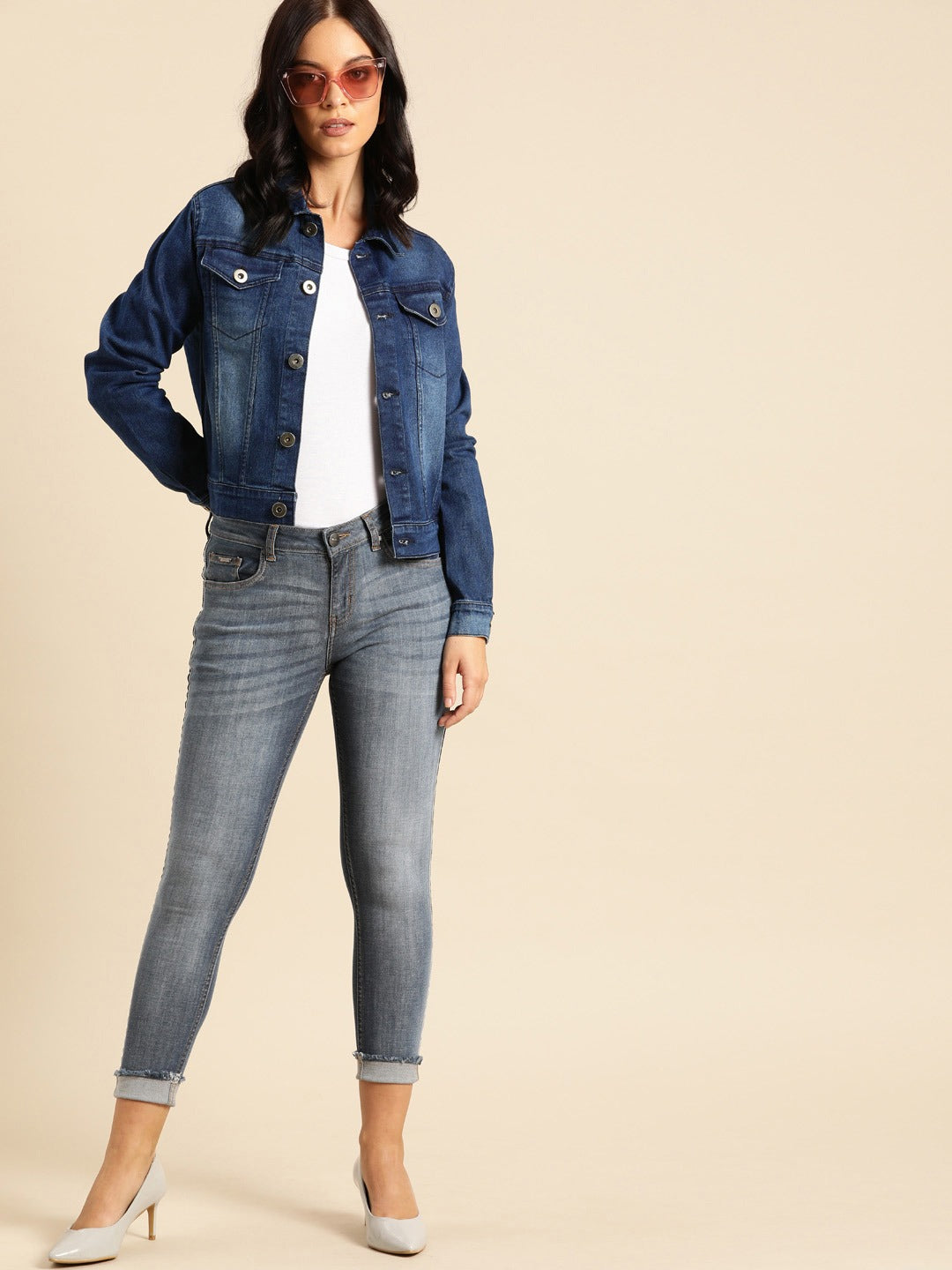 Stylish blue denim jacket and gray jeans worn by young woman in casual yet chic outfit, showcasing fashionable accessories including sunglasses.