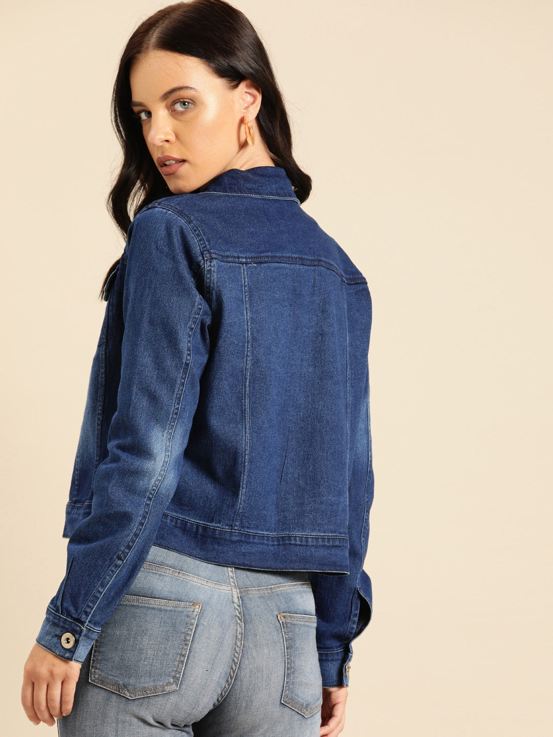 Dark blue washed women's denim jacket with standard collar and front button closure, worn by a young woman with long dark hair.