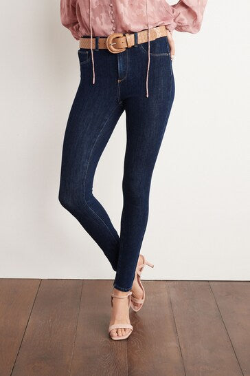 High-waisted stretch denim jeans with slim silhouette, showcased on a wooden floor.