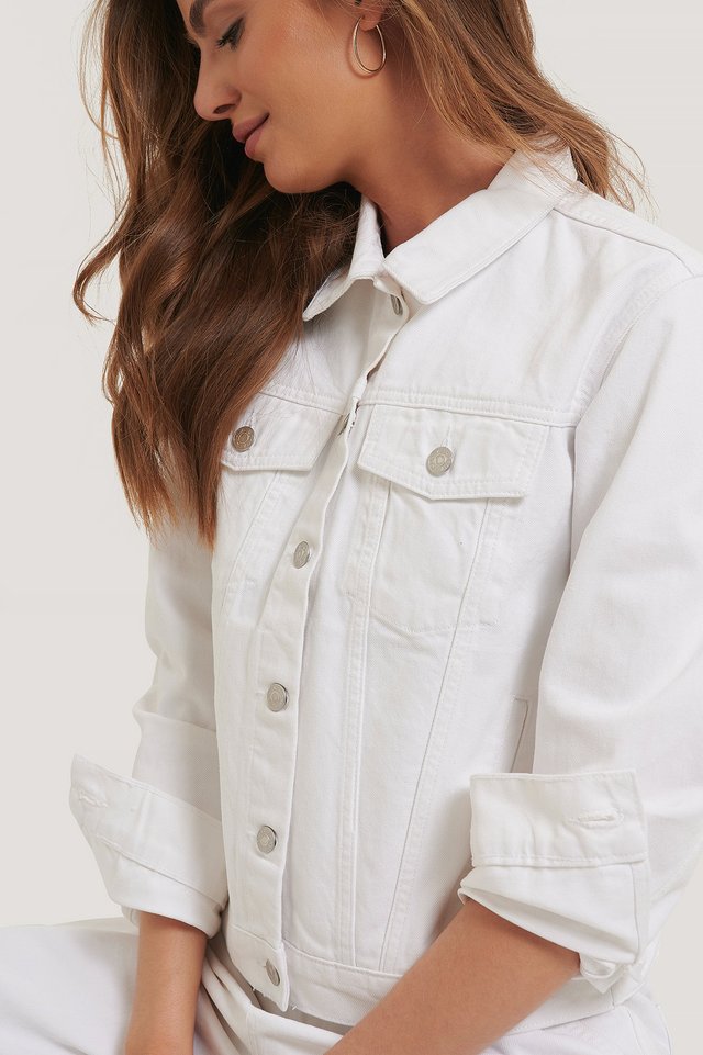 White solid women's denim jacket with button details, showcased on a young female model with long wavy hair.