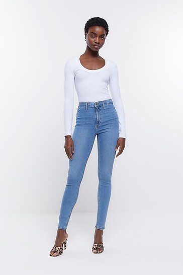 Stylish woman wearing light blue high-rise jeggings and a white top