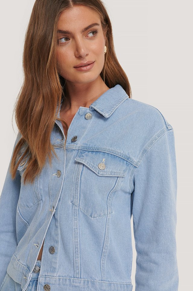 Light blue denim jacket for fashionable women, featuring front pockets and button closure.