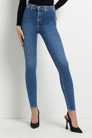 Stylish high-waisted blue denim jeggings with classic 5-pocket design, worn by a fashionable woman with black heels.