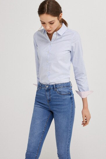 Blue wash jeggings with a figure-flattering stretch, worn with a classic white collared shirt.