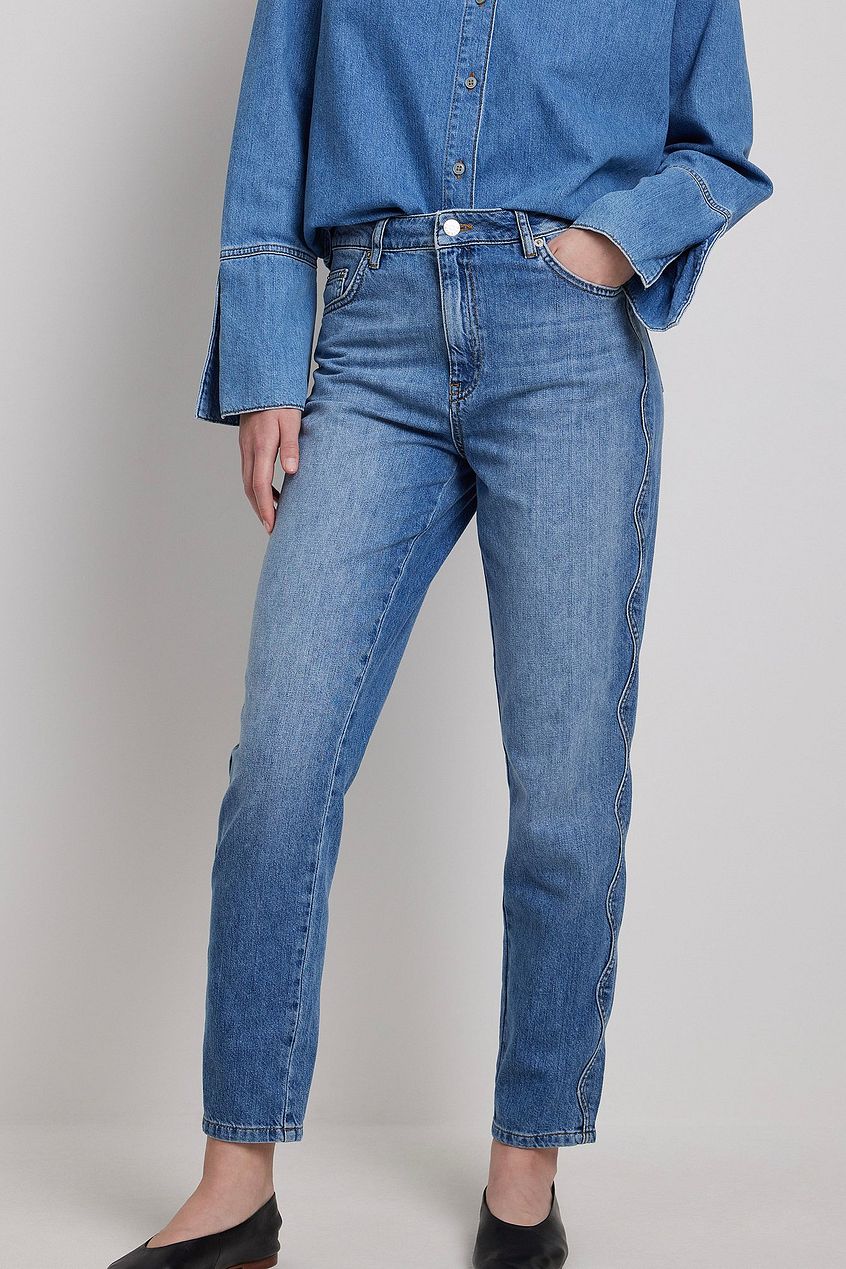 High-waist medium blue denim jeans with straight leg design, worn by a woman in the image.