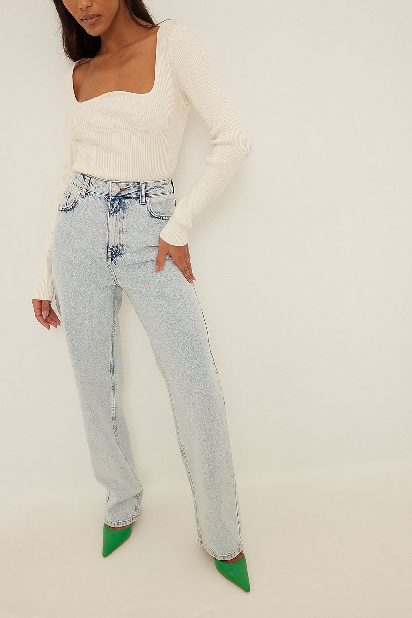 Distressed denim jeans with green heels, worn by a woman in a white top