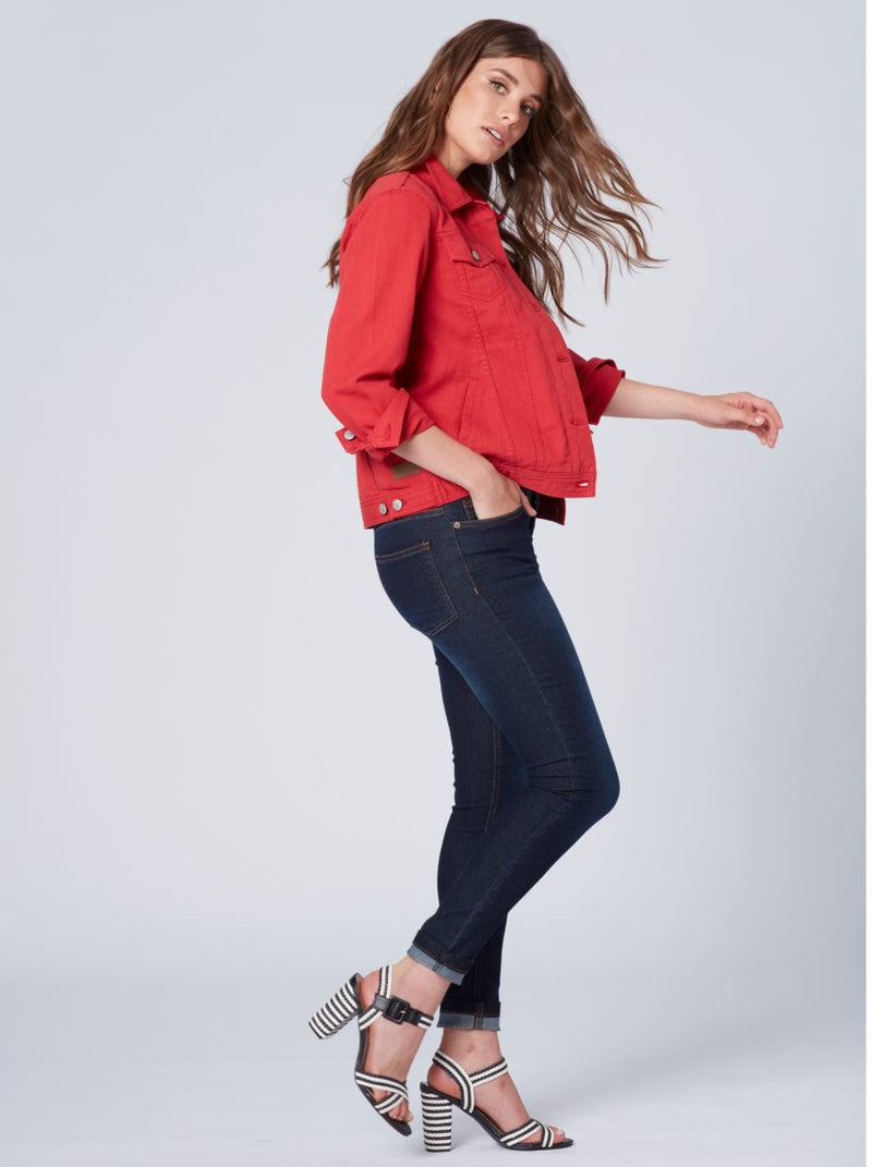 Vibrant red women's denim jacket, stylish loose fit, paired with dark blue skinny jeans and patterned high-heeled sandals, creating a fashionable, eye-catching look.