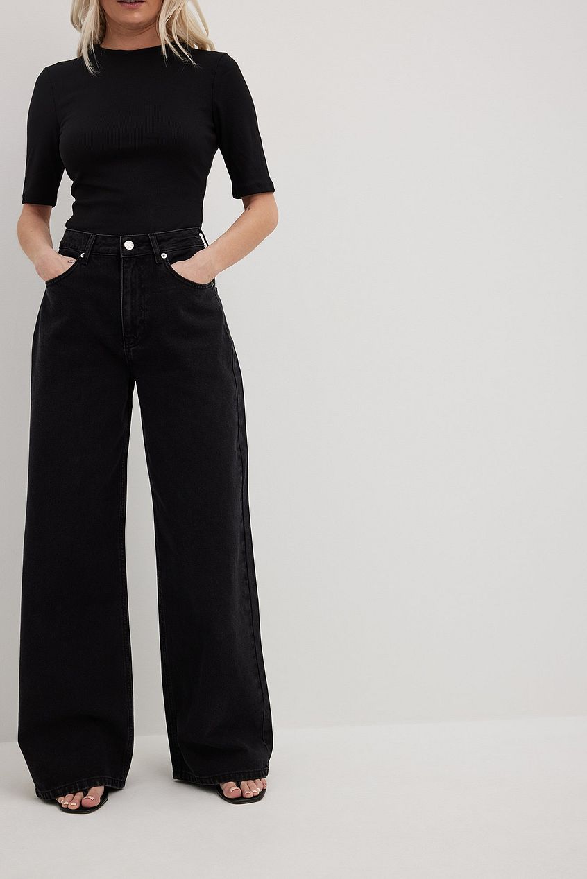 Organic Extra Wide Leg Denim jeans in black with high-waisted relaxed fit design, worn by a woman with blonde hair posing against a white background.