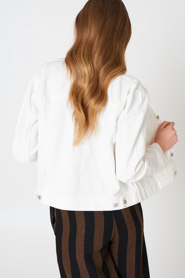 Stylish white denim jacket with wavy brown hair on model