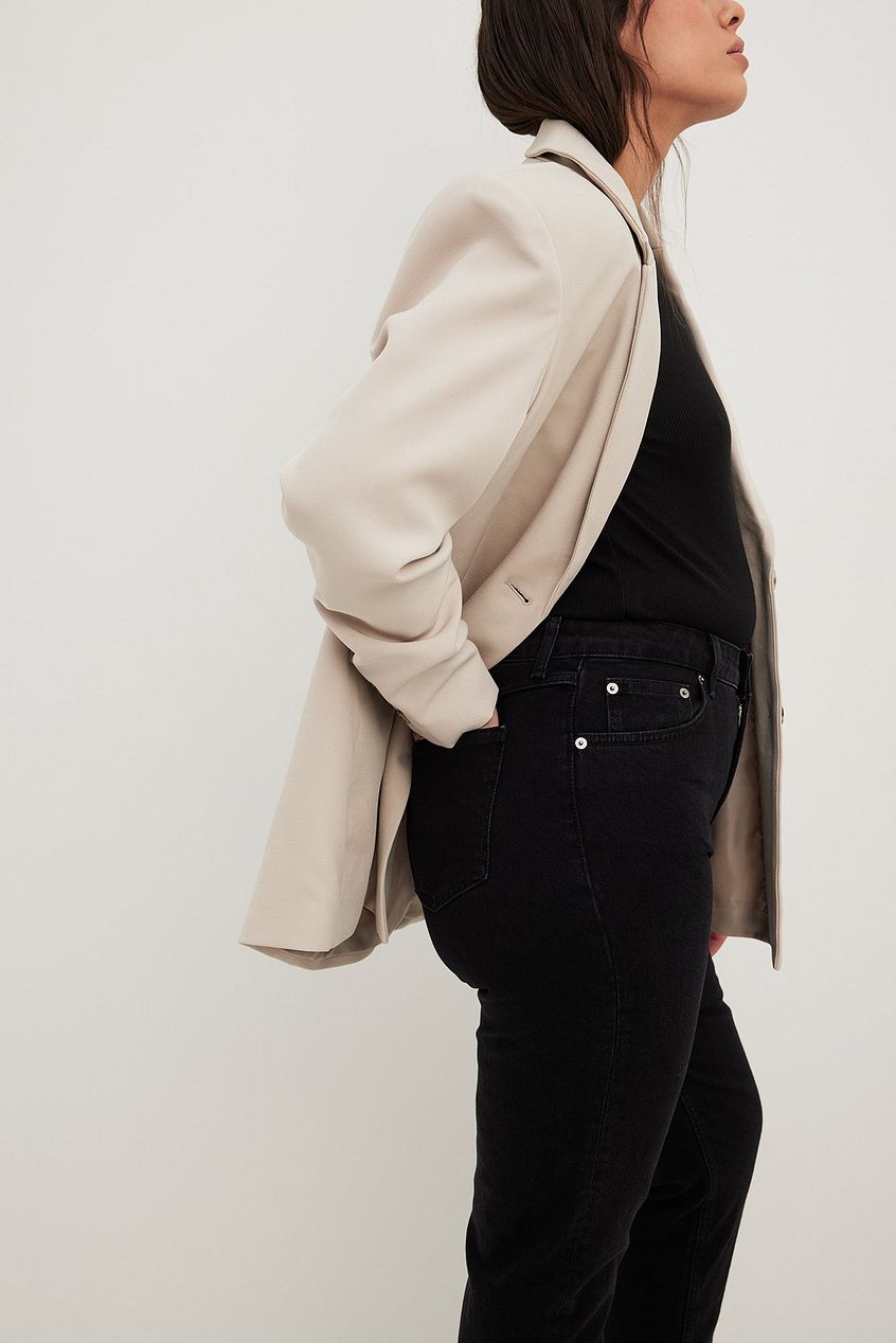 Stylish high waist black jeans with a beige oversized jacket, showcasing a contemporary and trendy look.