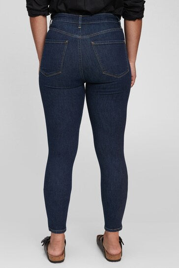 High waisted dark wash denim jeggings with ripped knee detailing, worn by a female model.