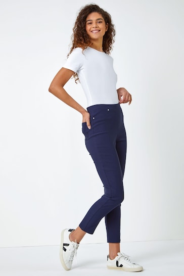 Confident woman wearing white top and navy blue stretch jeggings, showcasing stylish curvy figure in Ace Cart apparel.