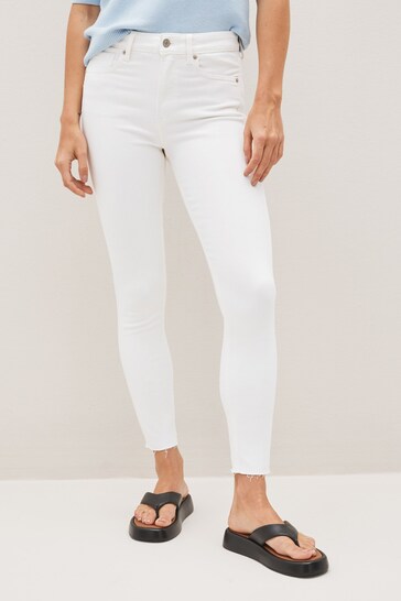 High waisted white stretch jeggings with ripped knees, worn by a female model