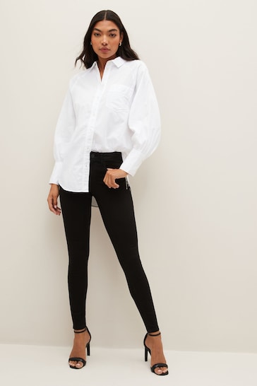 NOISY MAY Sculpting Stretch Skinny Jeans, high-waisted black jeggings, white button-up blouse, casual women's fashion, model posing in Ace Cart store.