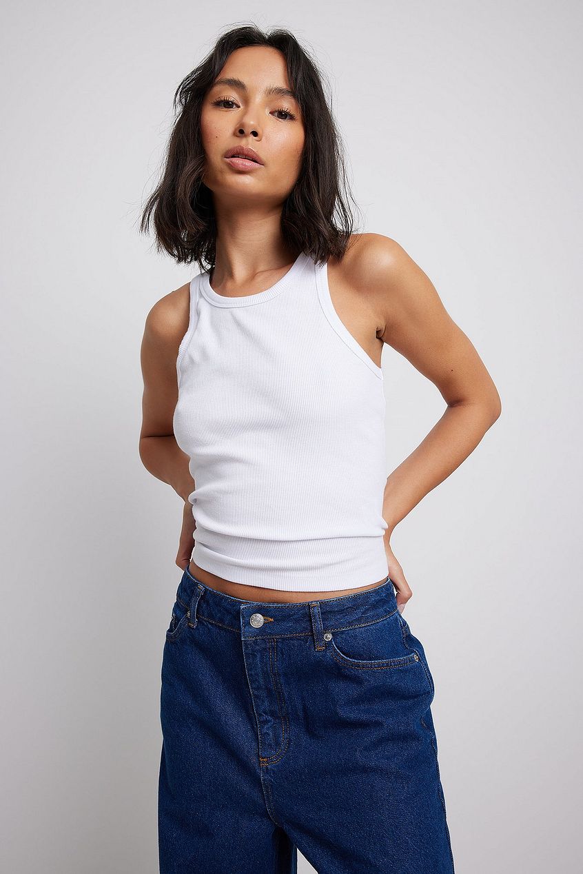 Low Waist Denim: Stylish woman wearing relaxed fit blue jeans and a white tank top from Ace Cart.