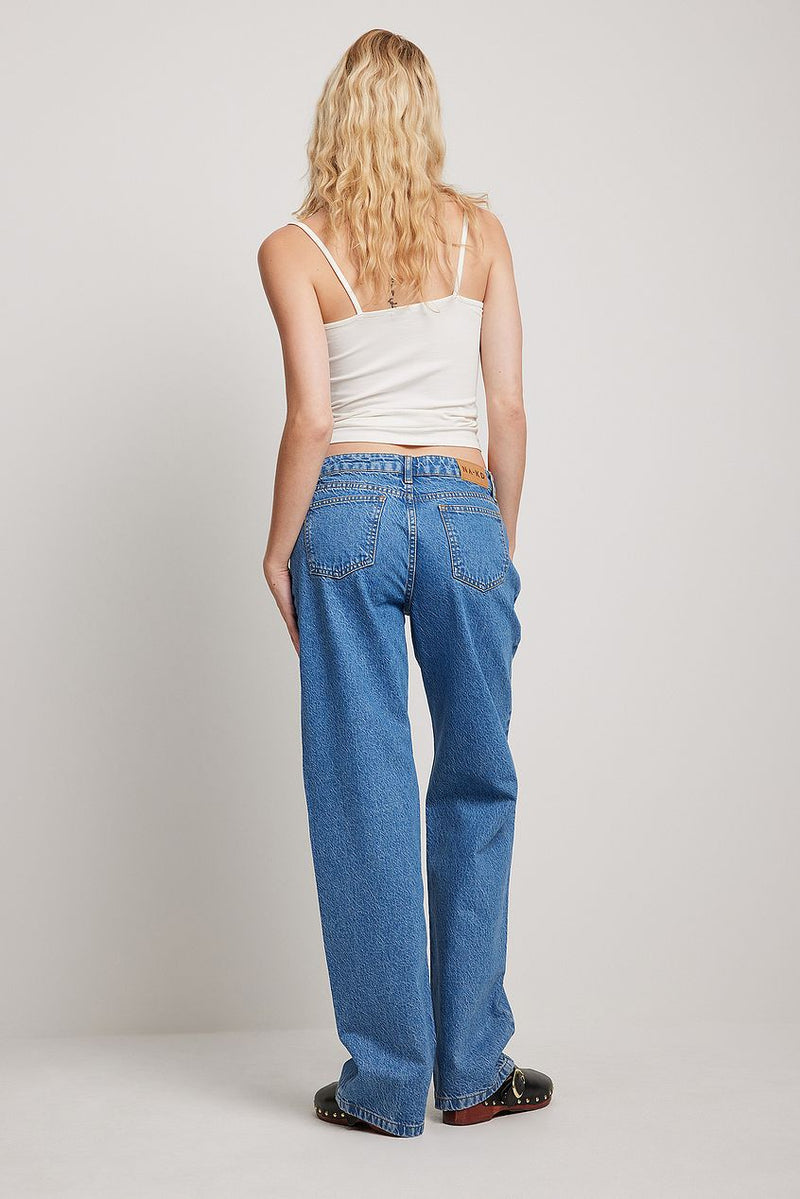 Stylish denim jeans with a slim leg silhouette displayed on a female model with long, curly blonde hair.