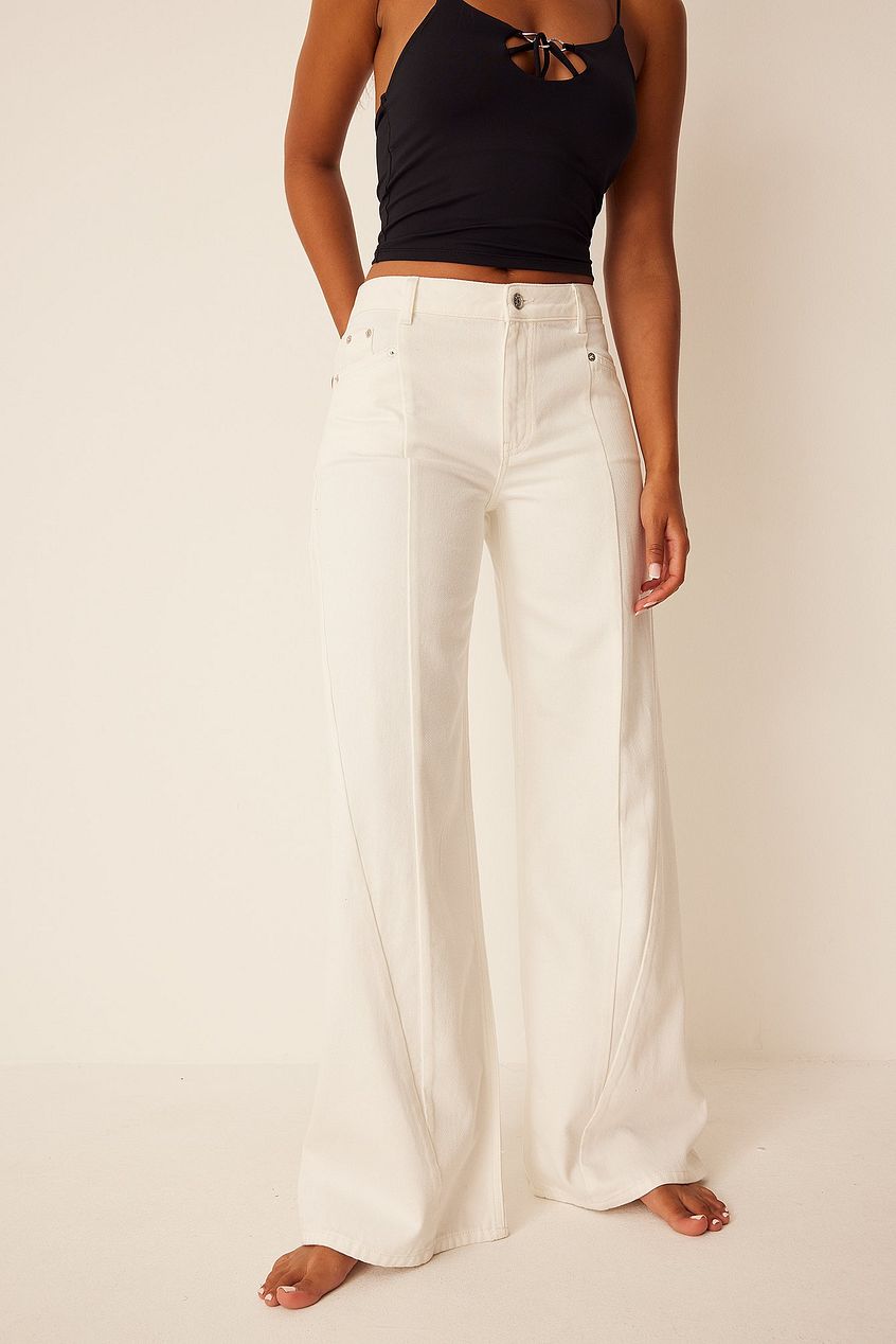 Mid rise straight denim jeans in a crisp white hue, showcased with a black halter top for a stylish, casual outfit.