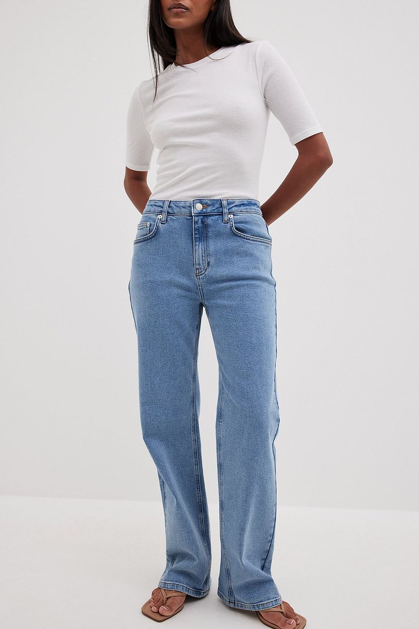 Relaxed fit mid waist denim jeans with a white top worn by a female model