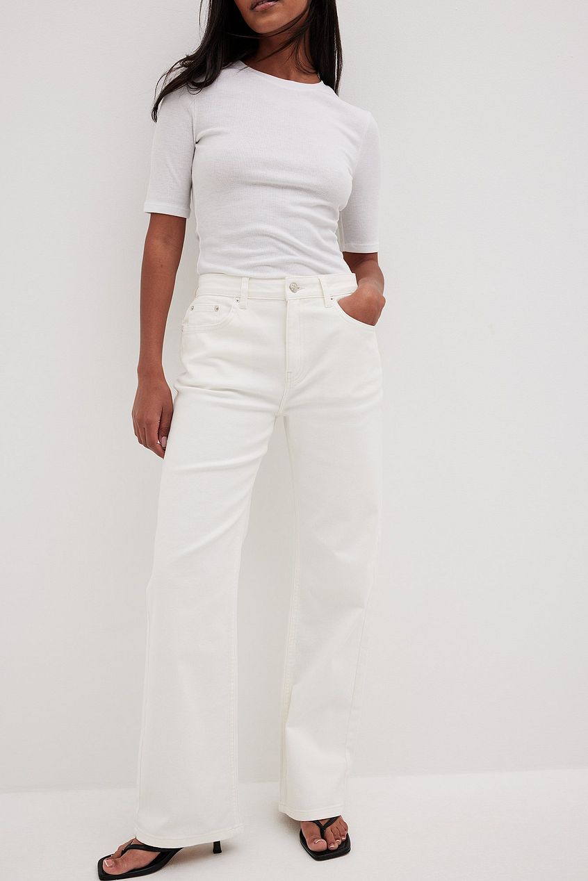 Mid Waist Denim: High-rise white denim jeans with a relaxed, straight-leg silhouette, showcased by a young woman in a simple white top.