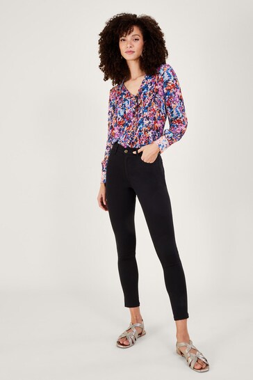 Vibrant floral print blouse with model wearing skinny black jeans in a Ace Cart clothing shop display.