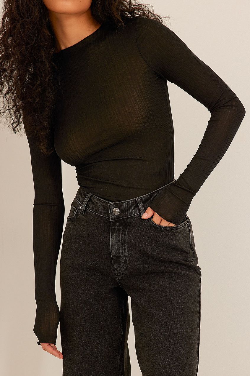 Black ribbed long-sleeve top and high-waist black denim jeans with raw hem details