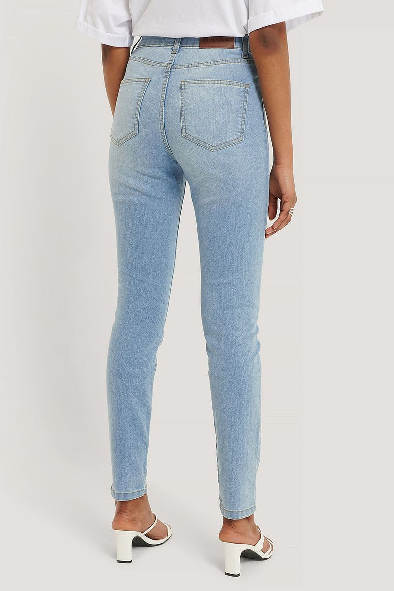 Light blue denim skinny jeans with fake pockets, worn by a model showing the back view.