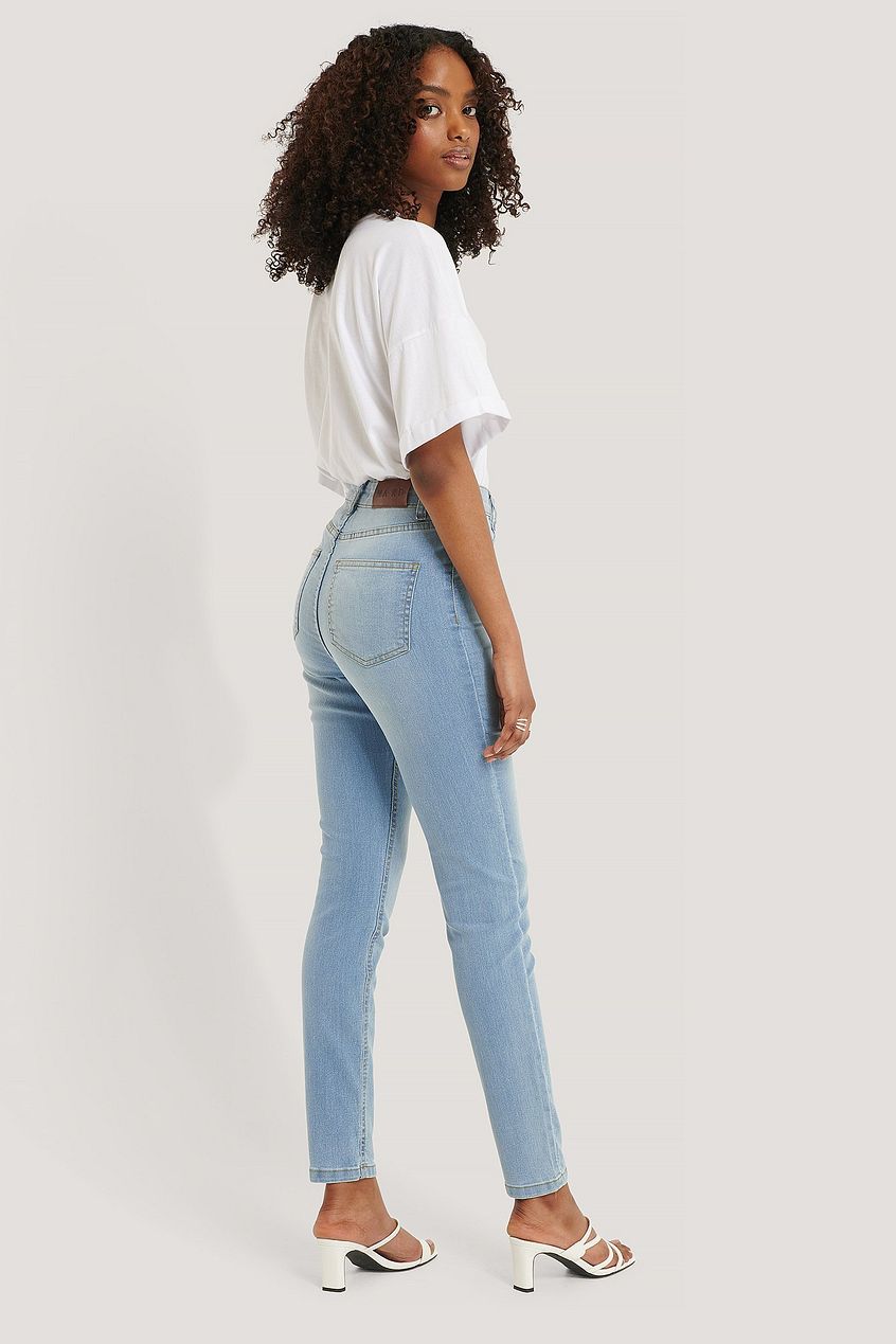 High-waisted skinny jeans in white top and stylish heels featured in image from Ace Cart.