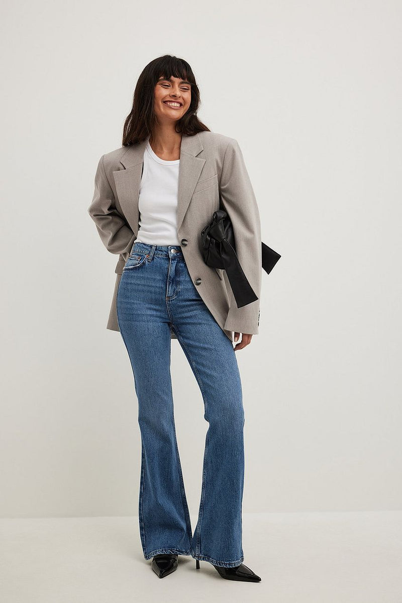 Stylish flared high waist jeans from Ace Cart, worn with a gray blazer and white top in a studio setting.