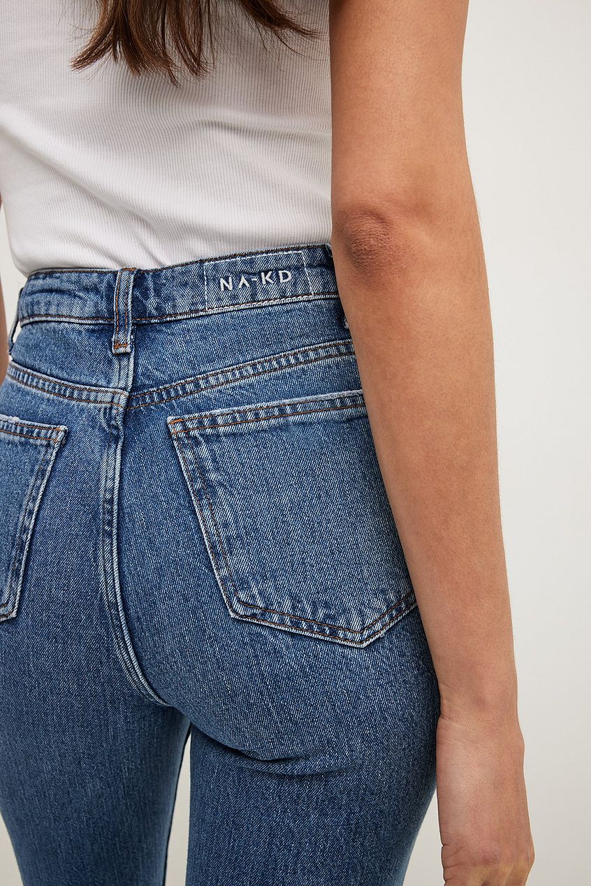 Denim high-waist flared jeans with minimalist branding on the waistband, showcasing a fitted, flattering silhouette.
