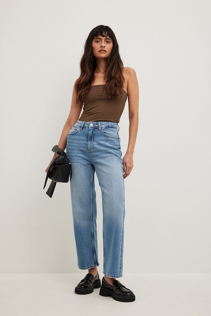 Straight high waist cropped blue denim jeans, brown sleeveless crop top, black leather ankle boots on woman with long dark hair