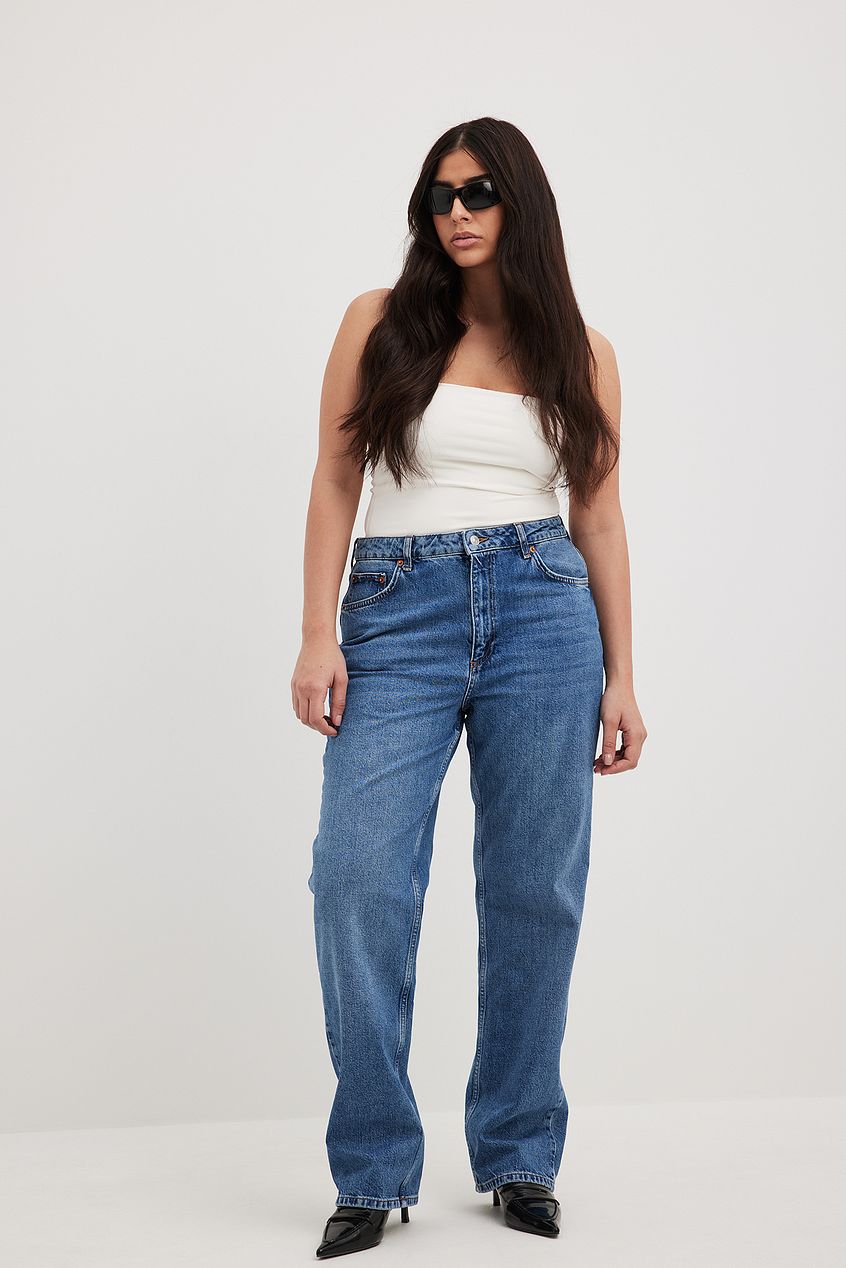 Straight high-waist blue denim jeans worn by a woman with long dark hair and sunglasses against a plain white background.