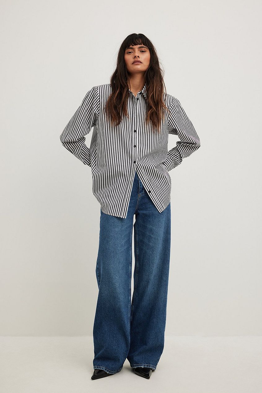 Wide striped blouse and high-waisted denim jeans worn by female model
