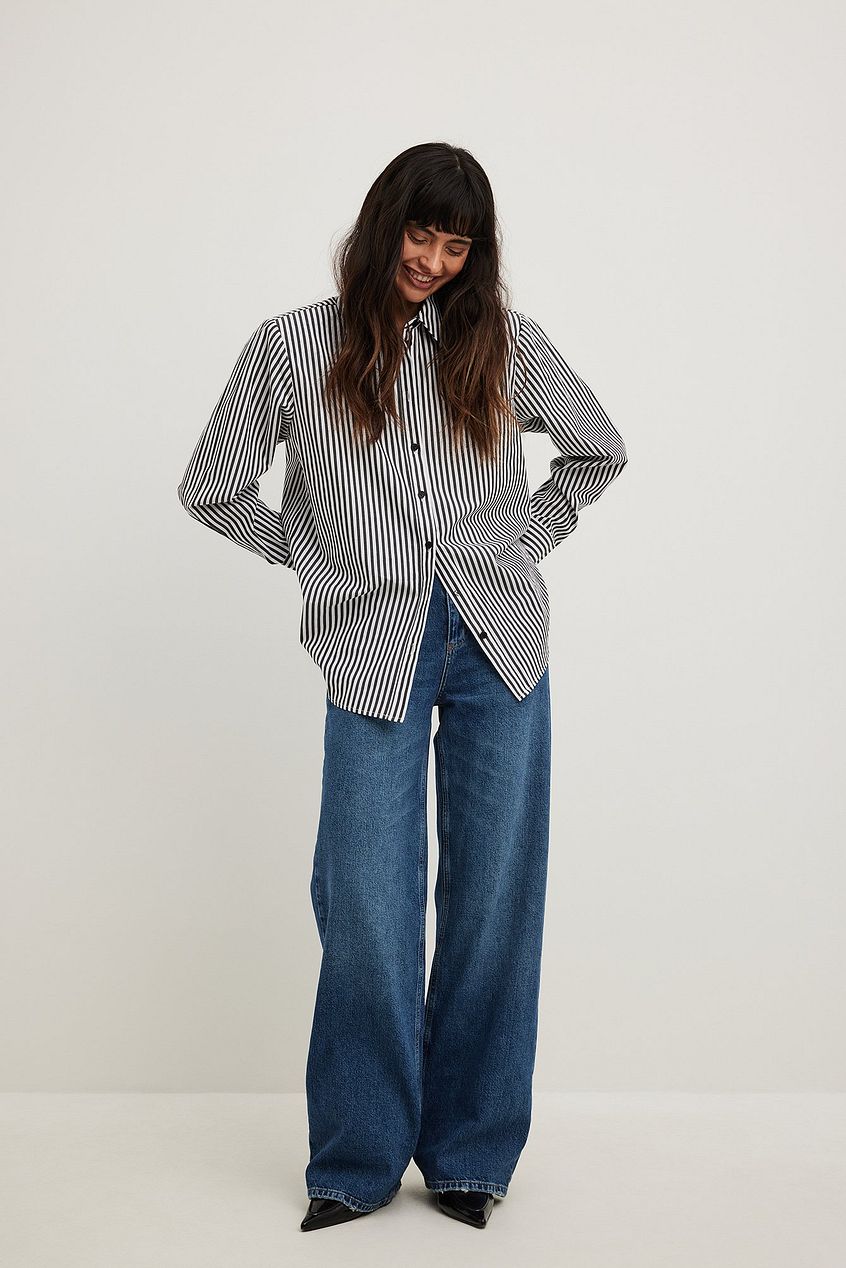 Wide high-waist blue denim jeans, striped button-up shirt, female model in casual fashion attire