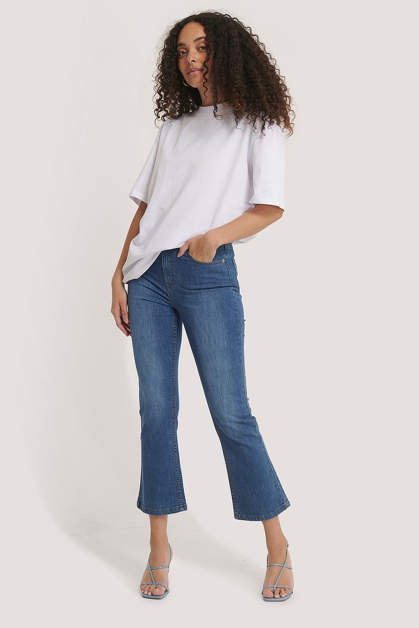 Relaxed fit denim jeans with a kick flare silhouette, paired with a simple white blouse for a stylish casual look.