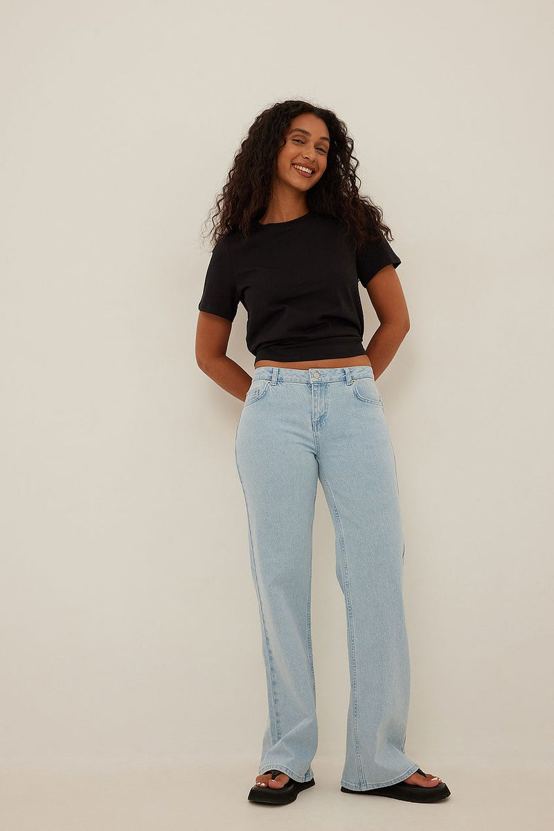 Stylish woman's casual outfit with low-waist light denim jeans and black crop top from Ace Cart's fashion collection.