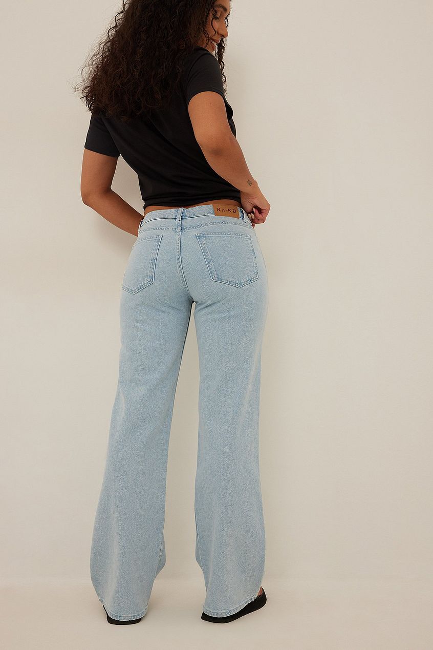 Low waist light blue denim jeans worn by a model with curly brown hair against a plain white background